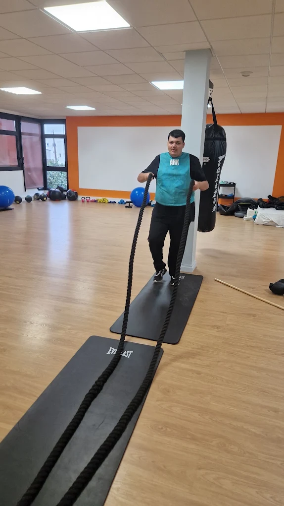 Jeune s'exerçant aux cordes ondulatoires en salle de boxe-fitness