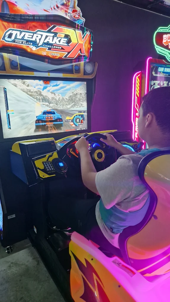 Jeune concentré sur un jeu d'arcade de course automobile